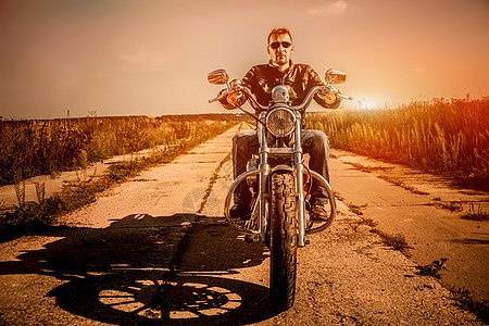 骑自行车的人穿着皮夹克太阳镜坐摩托车上看日落图片