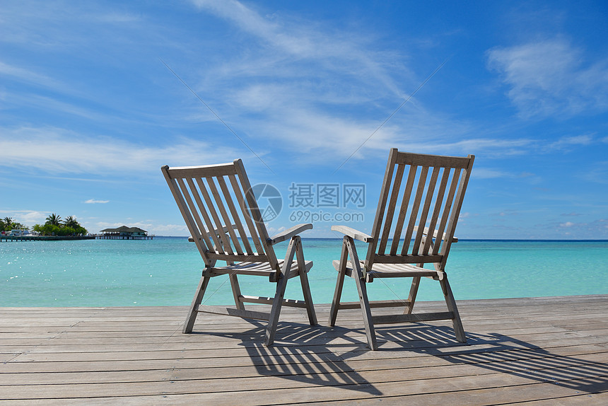 两张椅子床热带海滩的森林里,背景蓝色的海洋