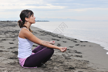 轻的女人清晨海滩上的莲花正丁冥想瑜伽图片