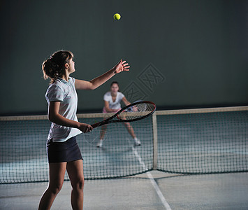 轻女孩网球场里打网球图片