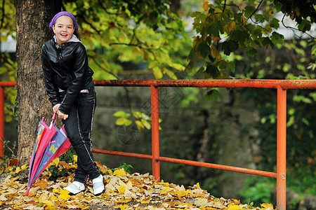 快乐的女孩带着雨伞公园里,秋天的雨天图片