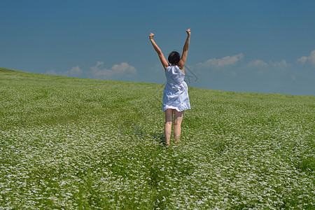 轻快乐的女人绿色的田野,蓝天的背景图片