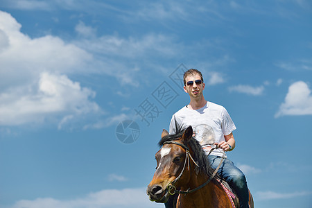 轻人骑马场动物,背景蓝天图片
