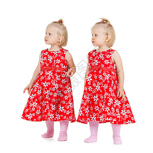 孩子双胞胎的两个相同的双胞胎女孩穿着红色的衣服,看着某个地方图片