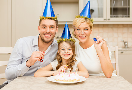 庆祝,家庭,节日生日幸福的家庭戴着蓝色的帽子,带着蛋糕蜡烛着喇叭图片