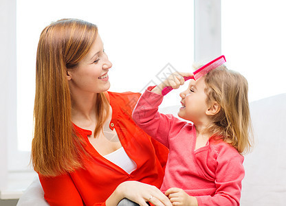 家庭,孩子幸福的人的幸福的母亲女儿用粉红色的梳子图片