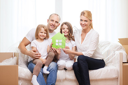 家庭,孩子,住宿家庭微笑的父母两个小女孩抱着绿色的房子图片