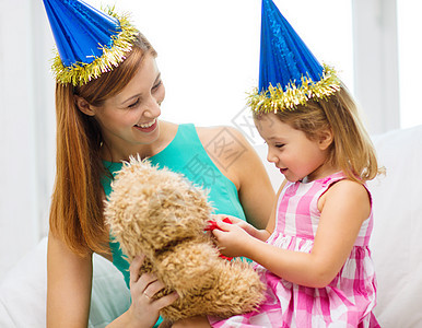 家庭,孩子,庆祝快乐的人的快乐的母亲女儿戴着蓝色的派帽泰迪熊图片