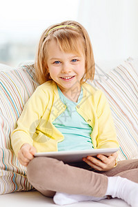 孩子,玩具,技术幸福的微笑的小女孩,平板电脑电脑坐家里的沙发上图片