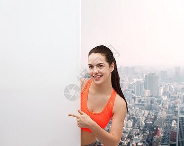 健身饮食微笑的十几岁女孩穿着运动服,手指指向白色空白板图片