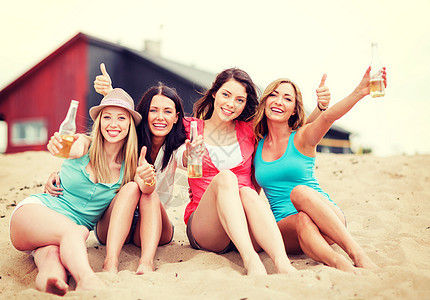 暑假假期女孩们喝着饮料,海滩上竖大拇指图片