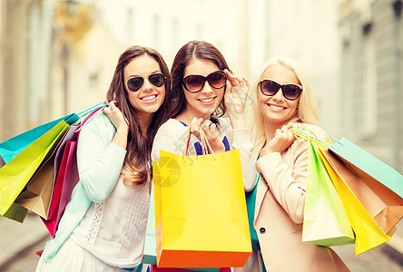 购物,销售,快乐的人旅游三个漂亮的女孩戴着太阳镜,带着购物袋图片