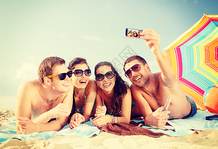 微笑的人在海滩上用智能手机拍照图片