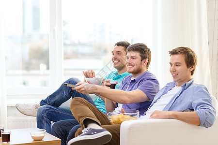 微笑的男生们吃比萨饼看电视在家里图片