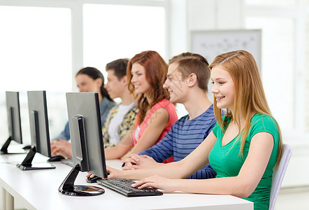 微笑的女学生与同学在学校上计算机课图片