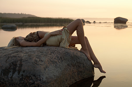 生气勃勃躺在岩石上的金发女生背景