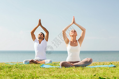 健身,运动,友谊生活方式的微笑的夫妇瑜伽练坐户外的垫子上图片