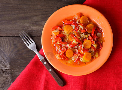 橙色盘子红色餐巾纸上炖蔬菜图片