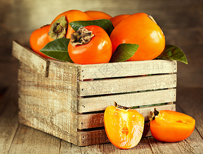 木制盒子里叶子的新鲜柿子图片