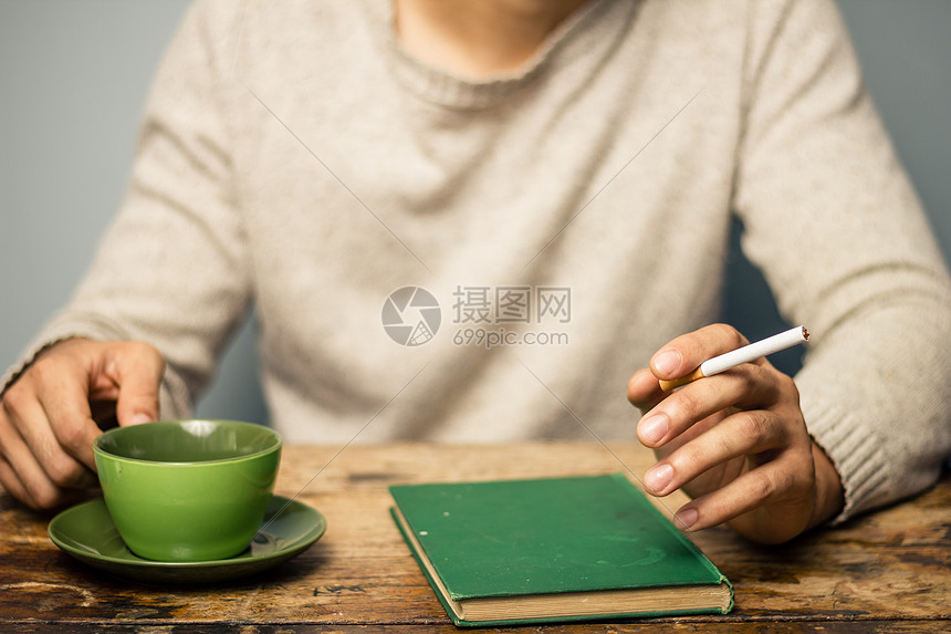 男人边看书边抽烟边喝咖啡