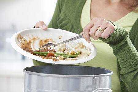 女人把食物剩菜刮进垃圾桶高清图片