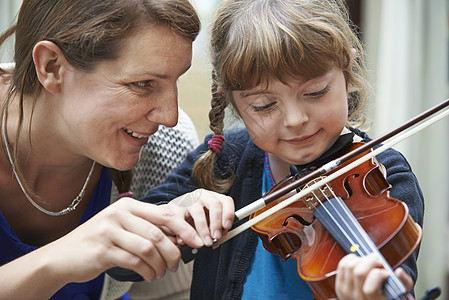 老师小提琴课上帮助轻的女学生背景