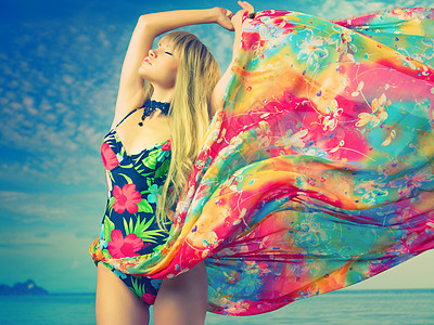 海滩上穿着彩色连衣裙的豪华金发女郎图片