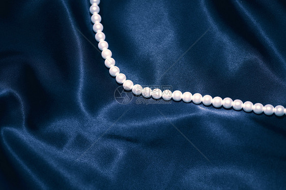 白色珍珠项链上的深蓝色丝绸特写图片