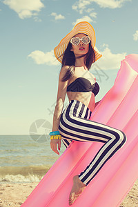 时尚的女人穿着时尚的泳衣海滩上图片