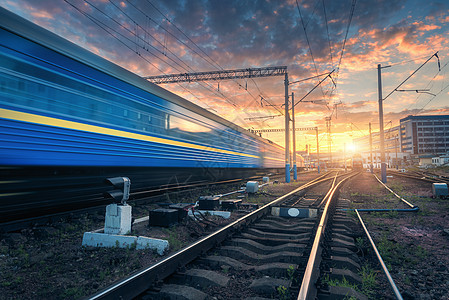 日落时铁路轨道上运动的高速客运列车火车站模糊的现代通勤列车,黄昏的时候,五颜六色的蓝天,红色橙色的云工业景观图片