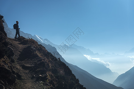 人站山上站山上看着山谷的轻女人风景与运动女孩,道路,山,蓝天与低云尼泊尔日出生活方式,旅行喜马拉雅山徒步旅行背景