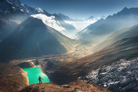 站山顶上的轻女人,日落时看着美丽的山谷,湖泊河流山丘风景与女孩,岩石云,天空,冰川尼泊尔旅行徒步旅行图片