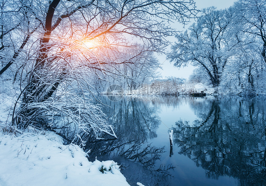 日落时河上的冬季森林五颜六色的风景与雪树冰冻的河流与倒影水中季节