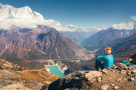 坐山顶上的轻女人,日落时看着美丽的山谷,湖泊岩石小山风景与女孩,岩石云,蓝天尼泊尔旅行冒险日落时图片