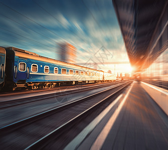 日落时,火车站里辆蓝色货车的漂亮火车工业景观与现代列车,铁路,铁路平台,建筑,多云天空与运动模糊效应图片