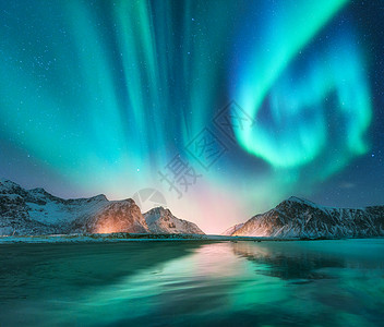 挪威洛芬岛的北极光极光绿色的北极光极地灯光的星空夜间冬季景观与极光,海洋与天空反射,石头,海滩雪山挪威洛图片
