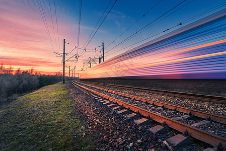 日落时铁路上运行的高速客运列车模糊的现代通勤列车火车站五彩缤纷的天空铁路旅游,铁路旅游工业景观运输高图片