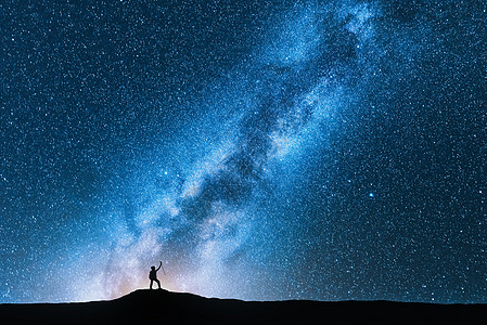 夜晚,带着跋涉杆的人神奇的银河上的剪影太空背景山上人的景观,明亮的银河,天空星星美丽的星系旅行蓝色的星图片