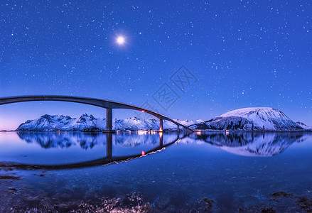 桥紫色的星空,美丽的倒影水中夜风景桥,雪山,天空满月明亮的星星反射海里挪威洛福滕岛的冬天桥紫色的星图片
