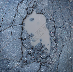 坑洞坑洞图像的破碎裂缝沥青路与脏水坑运输标志的道路维护汽车保险风险的汽车悬架图片