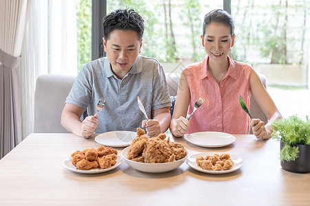 轻的亚洲夫妇吃炸鸡当代房子的客厅为现代生活方式的图片