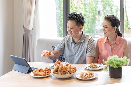 轻的亚洲夫妇吃炸鸡当代房子的客厅为现代生活方式的图片