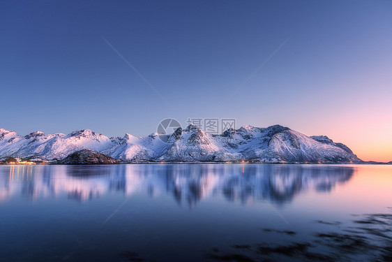 美丽的雪覆盖着群山,五彩缤纷的天空夜晚反射水中冬季景观海洋,雪岩,蓝天,倒影,日落时的阳光黄昏时分,挪威的洛芬岛图片
