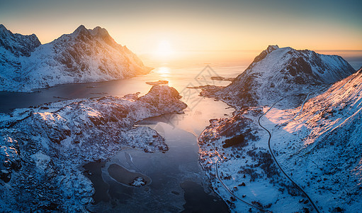 挪威洛福滕群岛日落时美丽峡湾的鸟瞰图冬天的风景雪山,蔚蓝的大海黄昏的太阳山顶上的岩石雪,道路,村庄北部海岸线图片