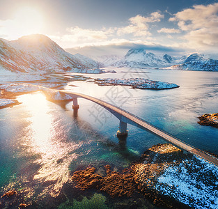 挪威洛福滕群岛海上雪山上的桥梁鸟瞰图弗雷德旺桥冬天的日落景观与碧水,岩石雪,道路天空与负荷的风景图片