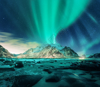 雪山上的极光,沙滩上石头挪威洛福滕岛的北极光极地灯光的星空夜间冬季景观与绿色北极光,岩石,照明图片