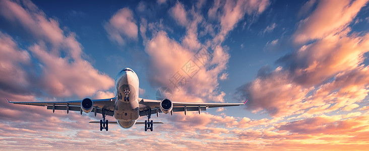五彩缤飞日落时降落五颜六色的天空上的飞机飞机的景观蓝天上飞着五彩的云乘坐客机的旅行背景商业飞机私人飞机背景