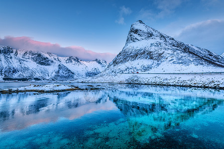 美丽的雪覆盖着群山蓝天,黄昏时云层反射水中冬季景观大海,雪岩,蓝天,倒影,日落洛芬岛,挪威黄昏图片