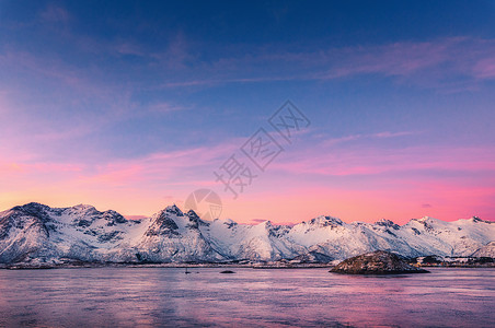 岩兰草美丽的雪覆盖着群山,五彩缤纷的天空黄昏时反射水中冬季景观与海洋,雪岩,紫色的天空,倒影,日落洛芬岛,挪威黄昏自背景