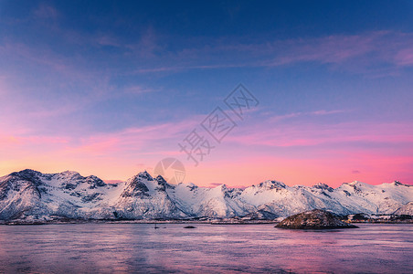 美丽的雪覆盖着群山,五彩缤纷的天空黄昏时反射水中冬季景观与海洋,雪岩,紫色的天空,倒影,日落洛芬岛,挪威黄昏自图片